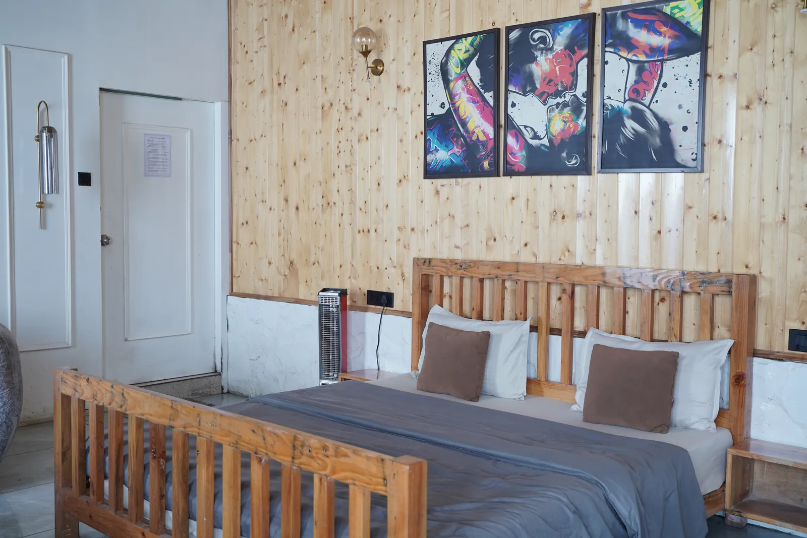 Wooden-panelled bedroom with double bed and colourful pop-art frames in Endless Sunset 1BHK cottage with jacuzzi, Highlanders, Suwakholi, Mussoorie