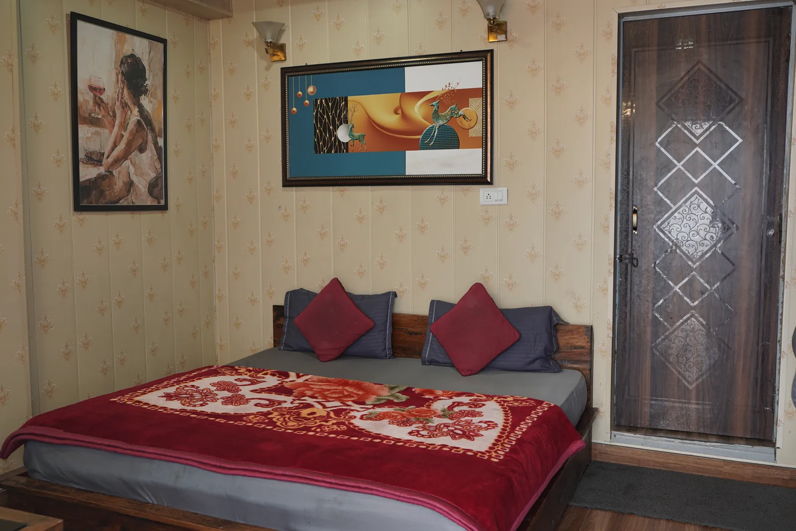 Simple double bed room with red cushions and wall paintings at Highlanders Café & Stay, an affordable mountain room in Suwakholi near Mussoorie