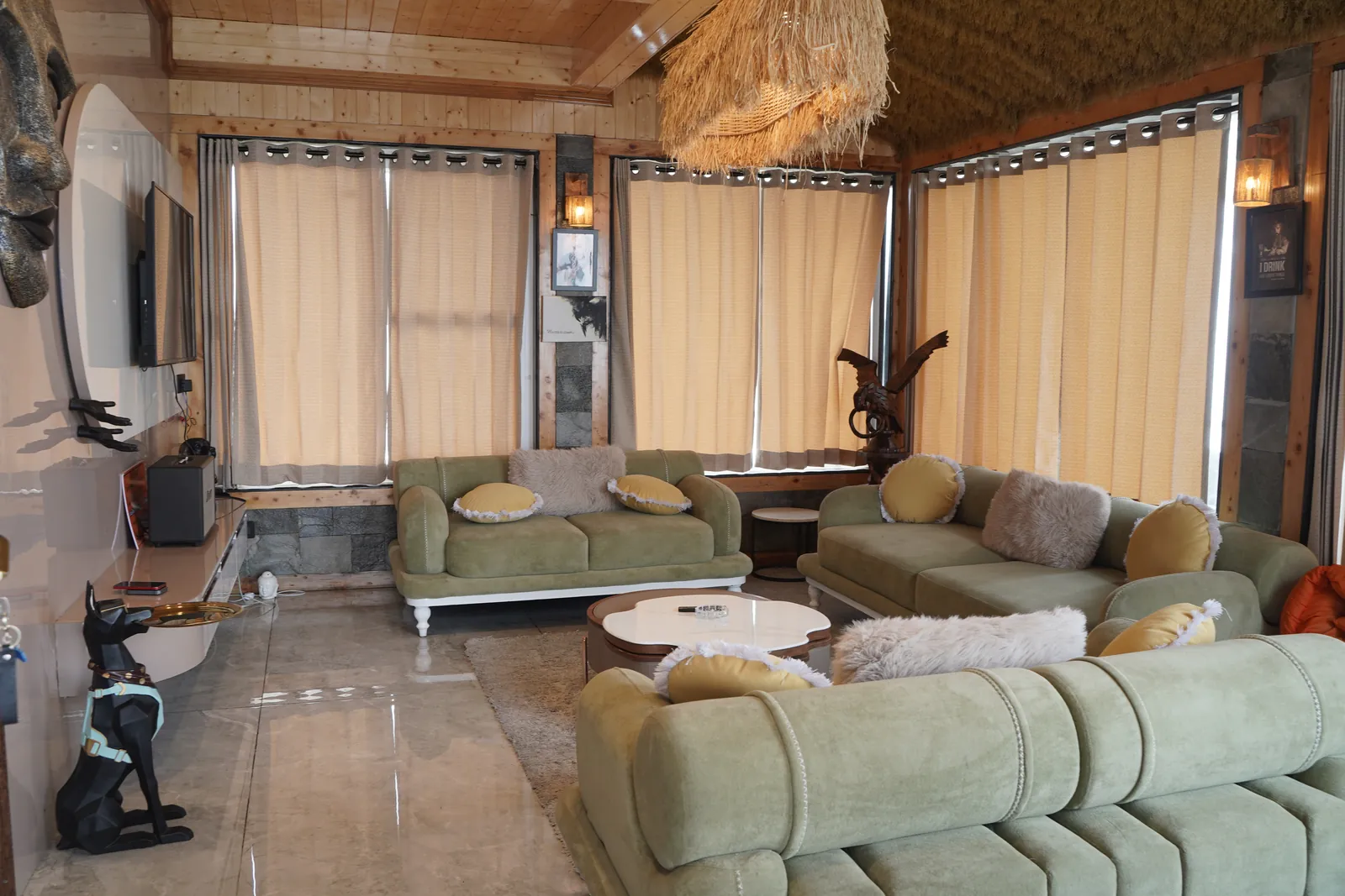 Spacious living room with green sofas, stone feature wall and large TV in The Kings Land 2BHK villa, Highlanders, Suwakholi near Mussoorie