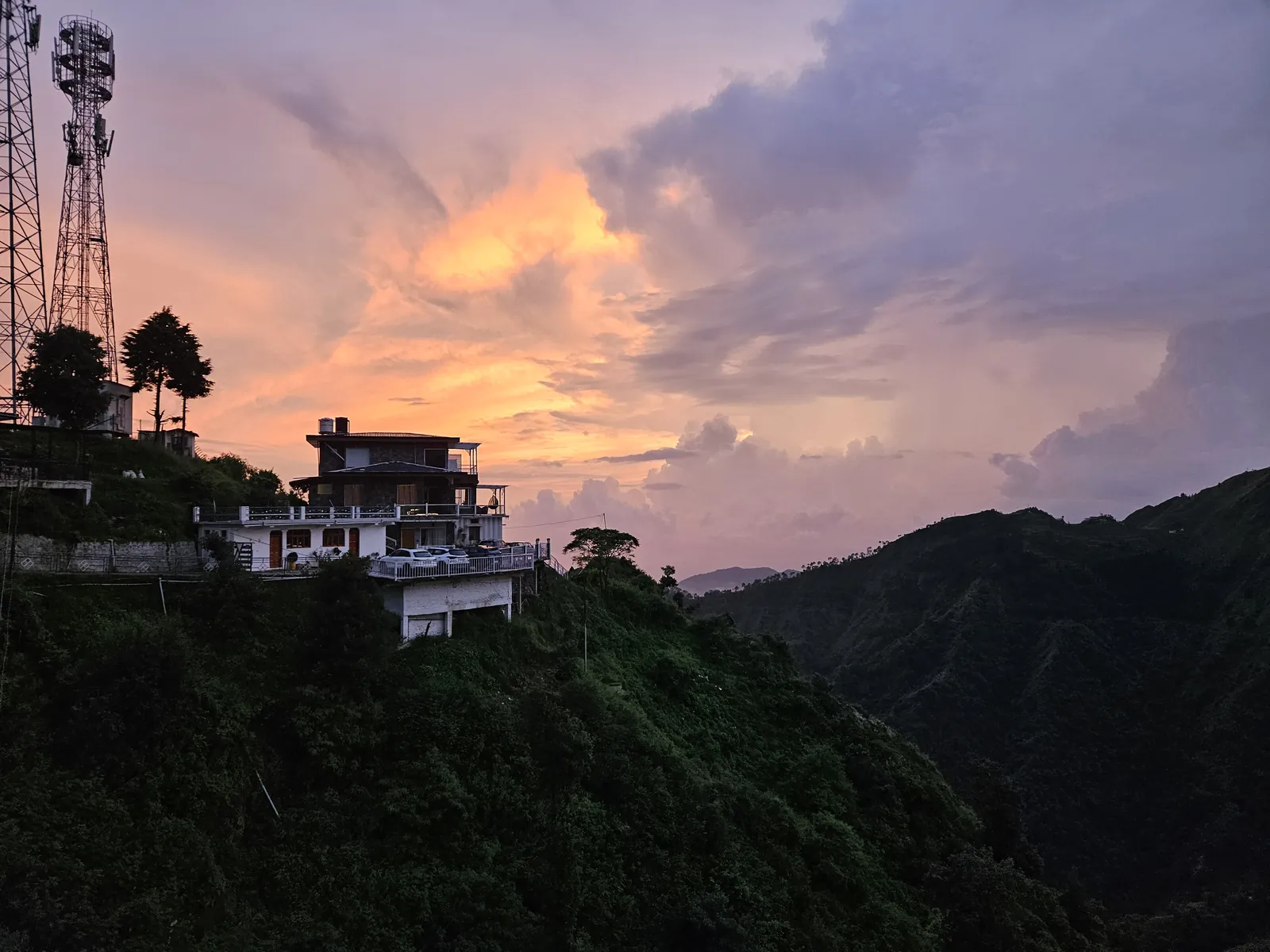 Golden orange sunset glowing over layered mountain ridges, seen from the Highlanders cottage stay in Suwakholi on Dhanaulti Road near Mussoorie